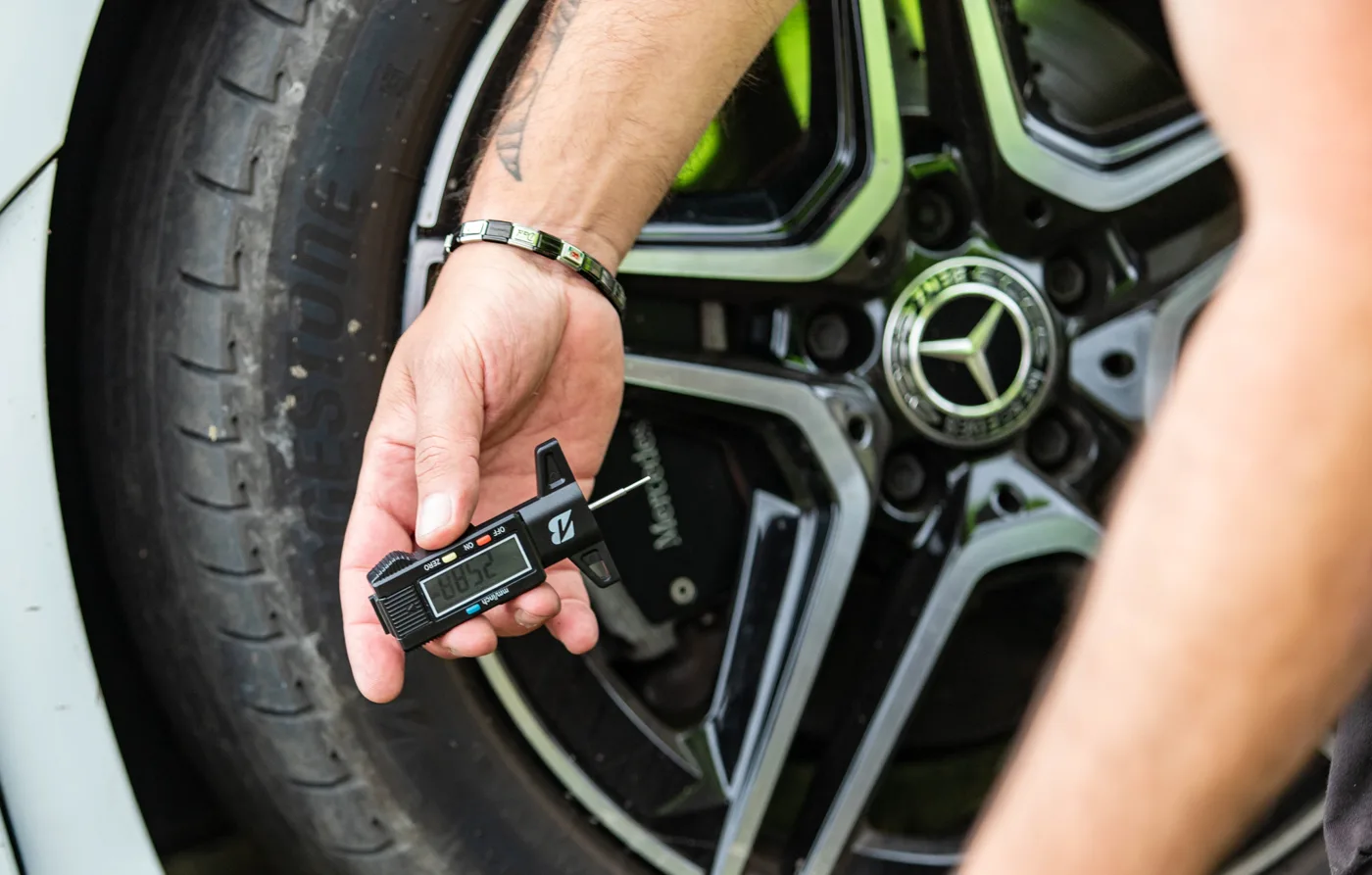 A digital gauge being used to measure the tread on a car tyre
