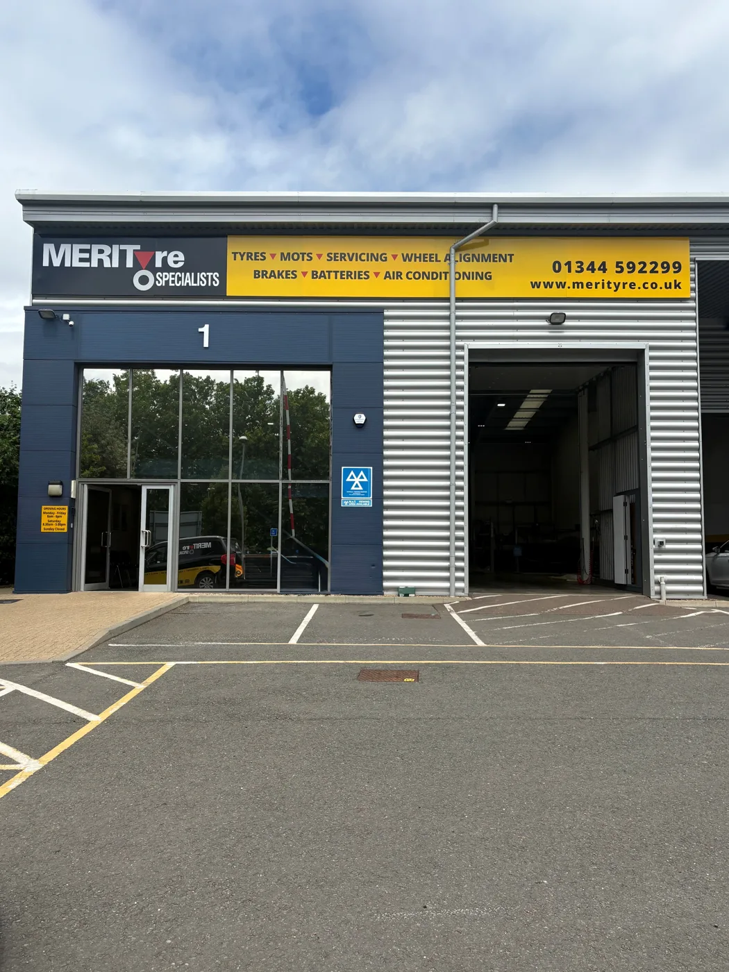 The front of the Merityre garage, with a yellow sign listing its services above the workshop door