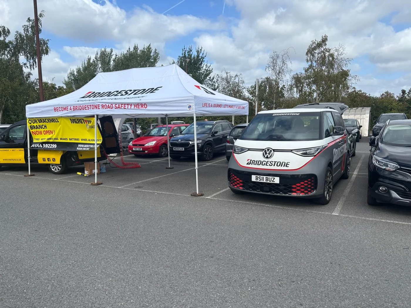 A Bridgestone branded Volkswagen ID. Buzz parked next to the Bridgestone gazebo and the yellow Merityre van